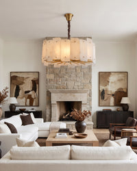 WOMO WM2391 alabaster chandelier above white sofas facing a stone fireplace in a living room.