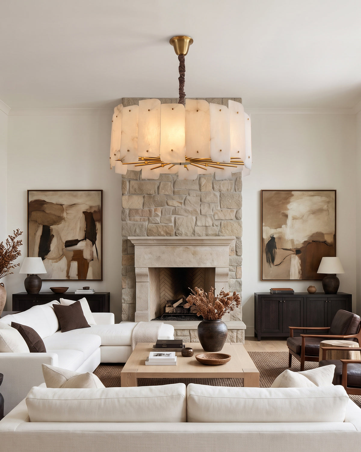 WOMO WM2391 alabaster chandelier above white sofas facing a stone fireplace in a living room.