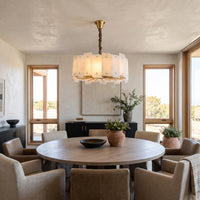 WOMO WM2391 glowing alabaster chandelier above a round dining table with upholstered chairs.