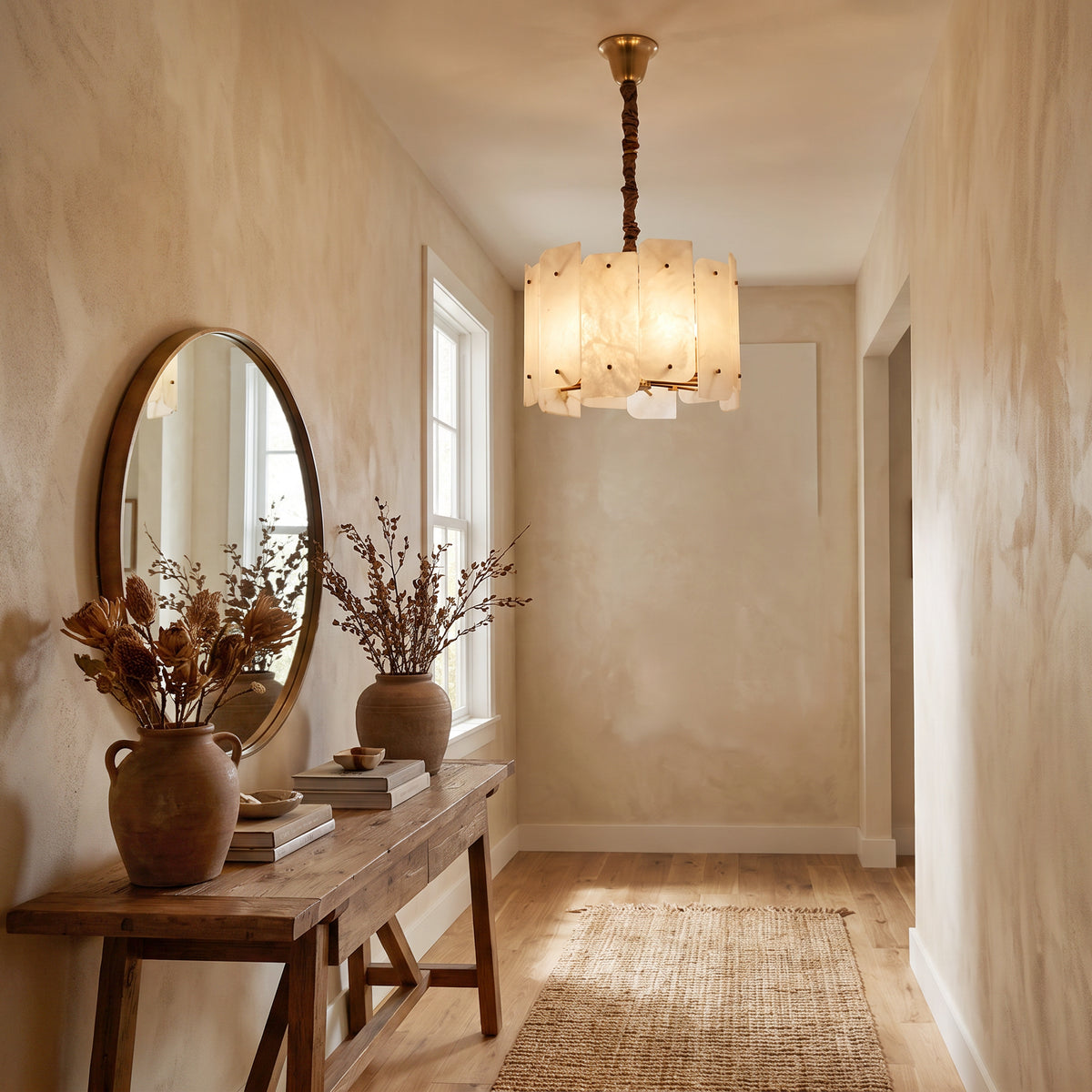 WOMO WM2391 illuminated alabaster chandelier in a narrow entryway above a wood console with dried flowers.