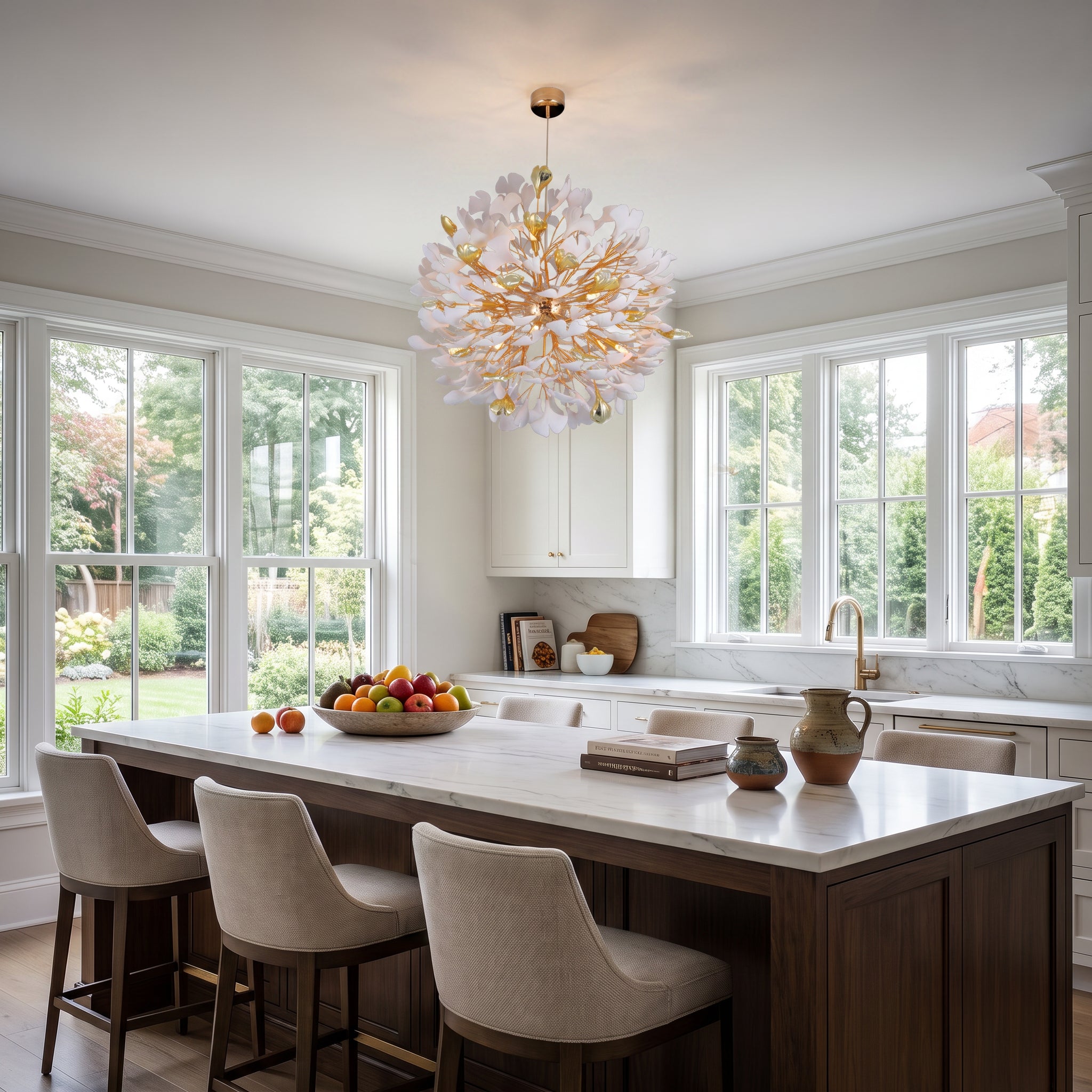 An elegant bright kitchen with a dark wood island and white marble countertop; a large white and gold chandelier with petal-like shades hangs above the island.