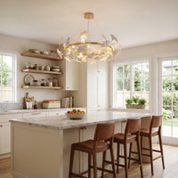White modern chandelier above a bright kitchen island, with ceramic ginkgo leaves and warm bulbs adding sculptural contrast.