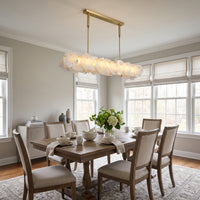 Modern linear alabaster chandelier hanging above a dining table, featuring translucent stone shades and a rectangular frame in a bright contemporary dining room