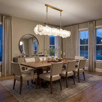 Modern linear alabaster chandelier installed above a dining table, featuring translucent stone shades and a rectangular gold frame in an elegant dining space